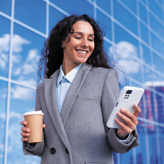 Woman smiling while holding phone and coffee