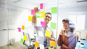 Business people looking at adhesive notes in conference room