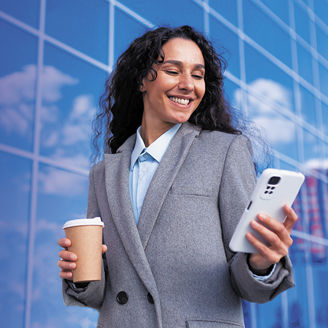 Woman walking with phone and coffee in her hands