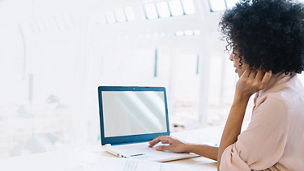 Back view of woman with curly hair operating laptop