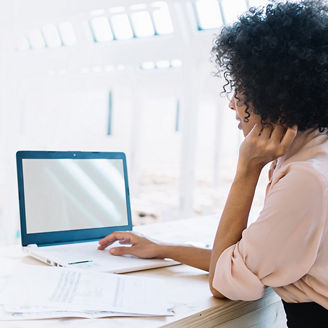 Een vrouw met krullend haar zit op haar laptop