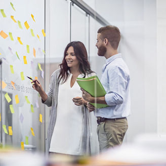 Des professionnels examinant des notes adhésives dans une salle de réunion.