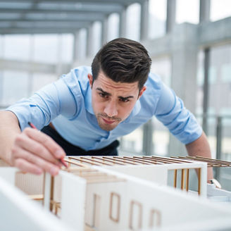Homme d'affaires ou architecte avec maquette d'une maison dans son bureau.