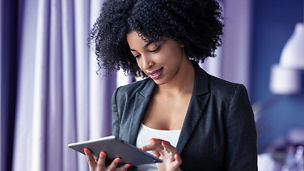 Portrait of smart afro young entrepreneur woman using her digital tablet while standing in the office at home.