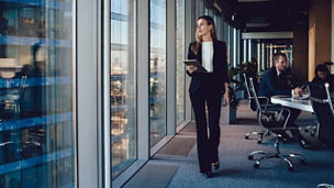 businesswoman holding a tablet, looking out the window