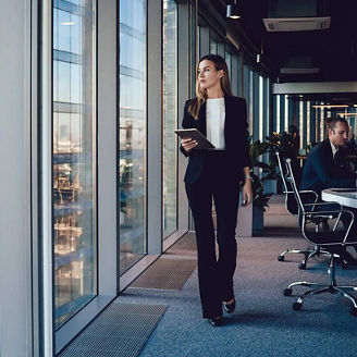 businesswoman holding a tablet, looking out the window
