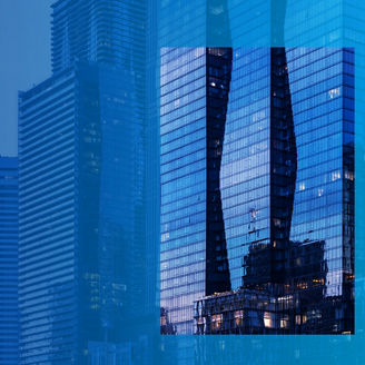 Städtische Skyline mit blauen Glasfassaden; zentrales Rechteck zeigt die Spiegelung zweier geschwungener Türme in der Fensterfront eines Hochhauses.