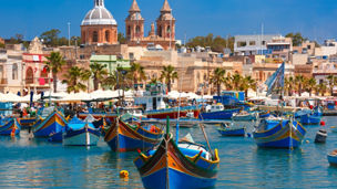 Traditional eyed colorful boats Luzzu in the Harbor of Mediterranean fishing village Marsaxlokk, Malta