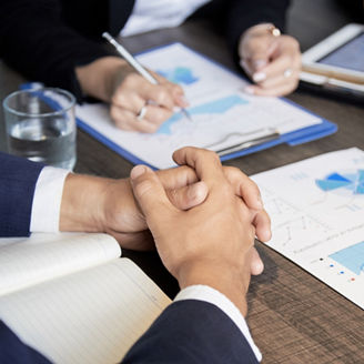 Crop shot of coworking businesspeople sitting at table with paper charts and tablet having meeting