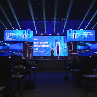 KPMG Business Leaders' Summit stage with screens showing the event's key visual and name