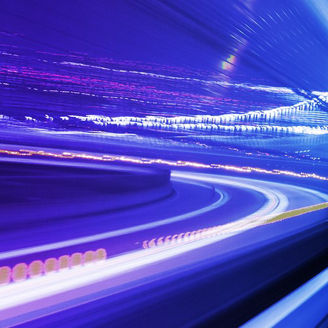 Trilhos luminosos em tons de azul e roxo criam um efeito de movimento e velocidade, evocando tecnologia e inovação.