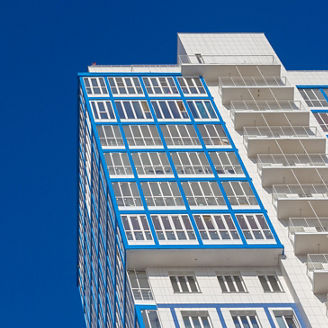 Bottom view of the facade of a high residential building against a blue sky