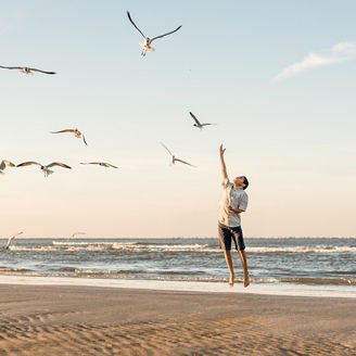 Boy playing with seagulls on beach