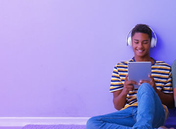 Two young boys interacting the a tablet and laptop