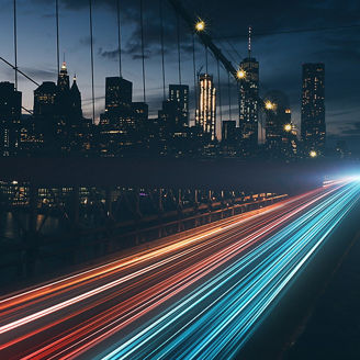 Lichter über Brücke vor Skyline bei Nacht