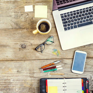 Mix of office supplies and gadgets on a wooden table background. View from above.