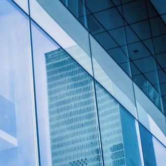 Edifício em vidro refletindo vários arranha-céus num ambiente de cidade