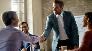 Business coworkers shaking hands during a meeting in the office. Focus is on a businessman.