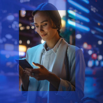 Zakenvrouw die op straat naar haar telefoon glimlacht.