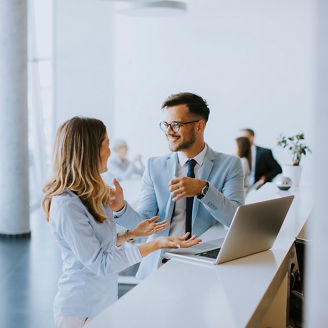 Young business couple working and discussing by laptop in the office in front of their team