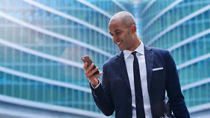 An business man in a suit and tie is happy and smiling while sending messages, working emails or calling using the phone. Concept of: technnology, network, success.