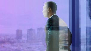 man looking out at city through window