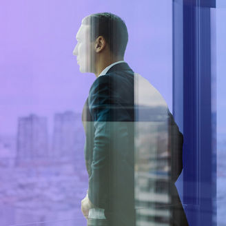 man looking out at city through window