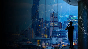 Businessman standing using smart phone in modern space watching city night view