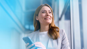 Business woman smiling and looking up while holding mobile phone