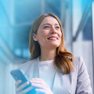 Business woman smiling and looking up while holding mobile phone