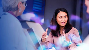 Business woman with laptop gesturing to colleages