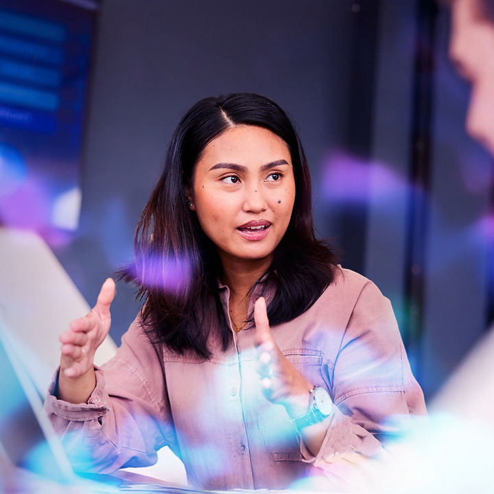 Business woman with laptop gesturing to colleages