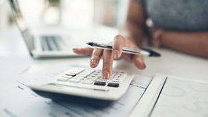 A person putting coins in a jar whilst using a pen and paper