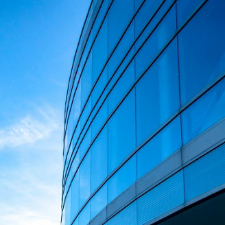 Building exterior with bright blue sky background. Building exterior with bright blue sky in the background on a sunny day. The interior of the building can be seen through the large glass windows.