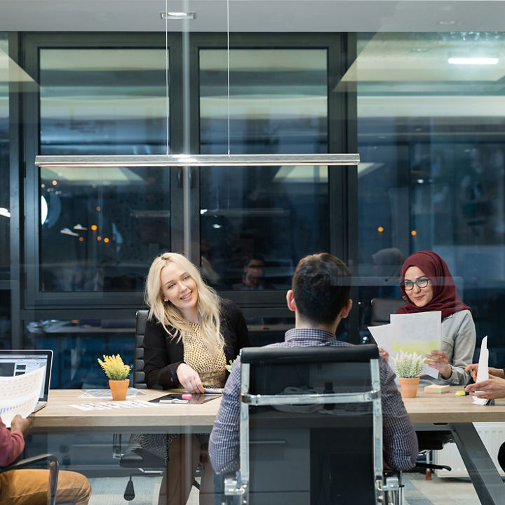 Group of individuals in a meeting, including women in hijab.