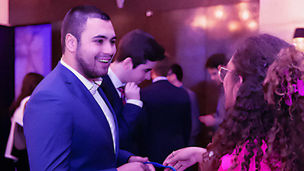 Young man in a blue suit smiling and chatting with colleagues at a professional event