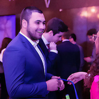 Young man in a blue suit smiling and chatting with colleagues at a professional event