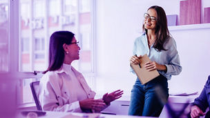 Woman with glasses holding notebook and smiling