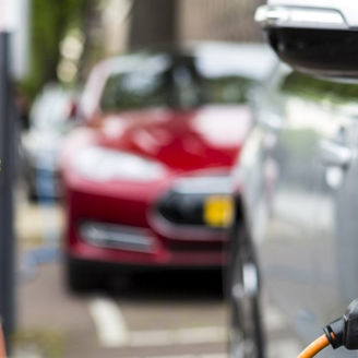 Een elektrische auto laadt aan een paal