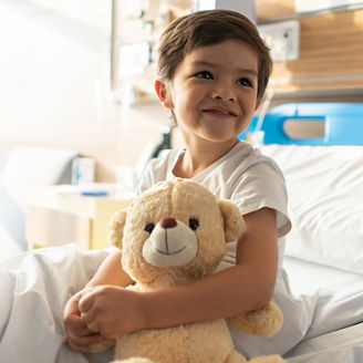 Child smiling and holding a soft toy