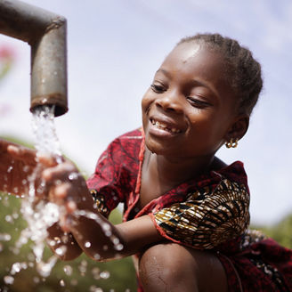 Child washing her hands under a water tap