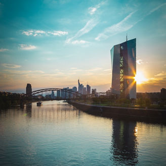 city-view-with-tall-building-in-focus-at-riverbank-sun-blue-sky-and-bridge