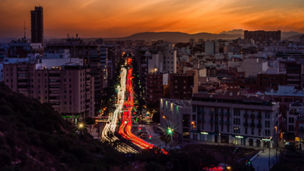 A city with modern buildings and motion light effect under a blue sky during an orange sunset