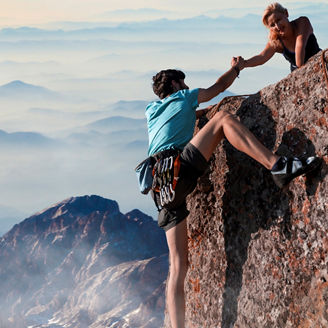 Friends helping each other climing a mountain