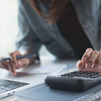 Close up, business woman working on laptop and using calculator to calculate business report at office. accounting, doing finance and tax calculation