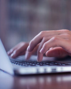 Close up view of hands typing on a laptop keyboard