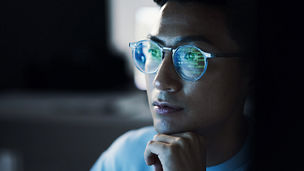 A person with glasses on looking ahead whilst resting their head on their arm