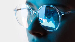 Close up view of blue eye in glasses with futuristic holographic interface to display data. Portrait of beautiful young woman, half of face. Augmented reality, future technology, internet concept.
