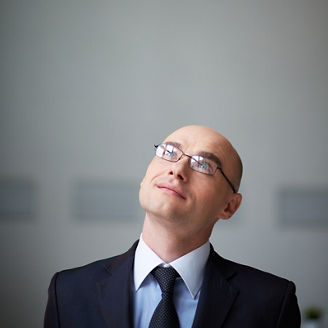 Portrait of attractive businessman in eyeglasses looking upwards