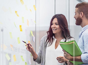 Colleagues having a discussion near a glass with sticky notes